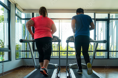 Two Asian trainer man and Overweight woman exercising training on treadmill in gym. Fat women take care of health and want to lose weight.