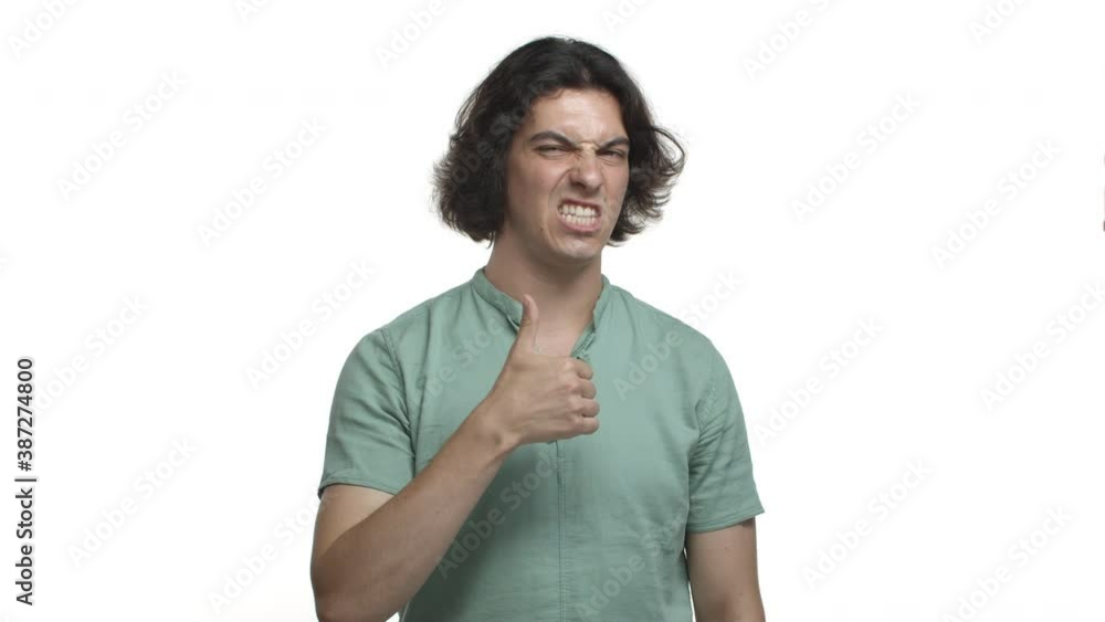 Handsome adult man with long hairstyle, showing thumbs-up and smiling cheeky, praise you, making compliment, standing over white background Handsome adult man with long hairstyle, showing thumbs-up and smiling cheeky, praise you, making compliment, standing over white background