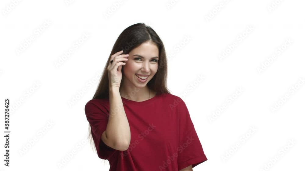 Young beautiful woman in red t-shirt flirting with you, tucking hair behind ear and smiling coquettish, standing sensual over white background Young beautiful woman in red t-shirt flirting with you, tucking hair behind ear and smiling coquettish, standing sensual over white background