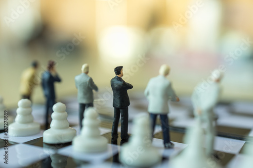 Business, Teamwork Concept. Group of businessman miniature figure people standing on chessboard with chess pieces.