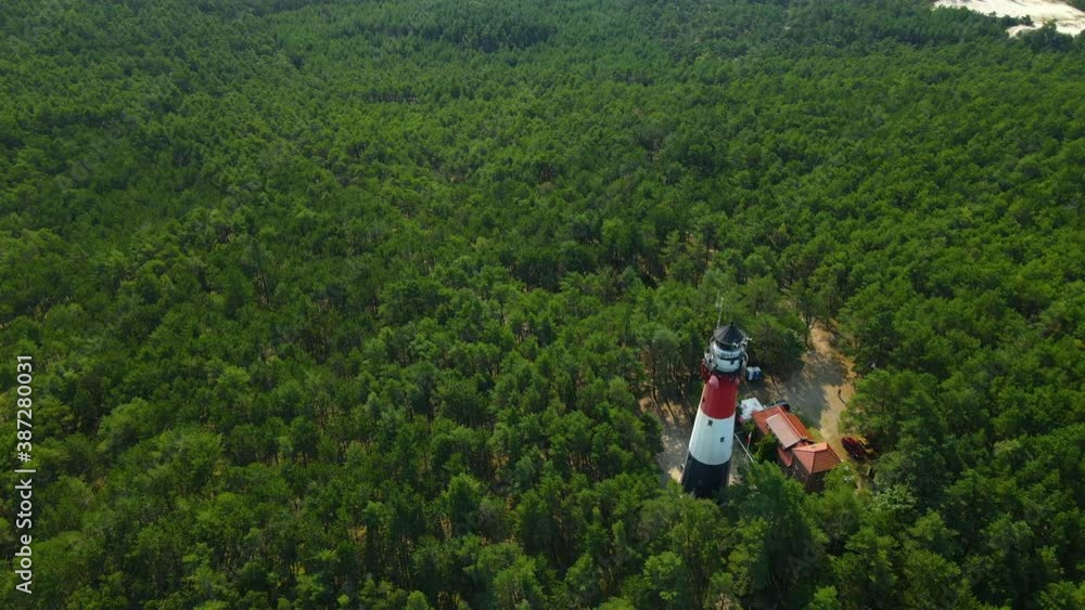 Incredible White and red light House stands tall above trees in a dense forest as a drone circle orbits around Incredible White and red light House stands tall above trees in a dense forest as a drone circle orbits around