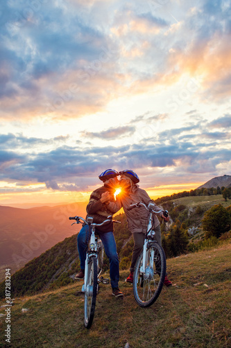 elderly couple with bicycles standing at the mountain park kissing