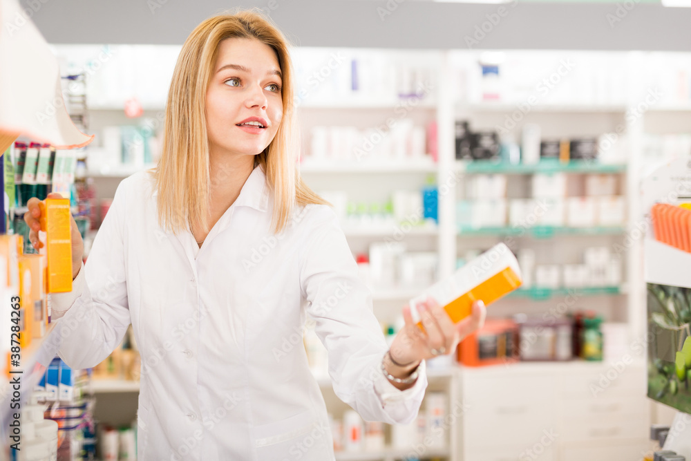 Positive woman pharmacist working in pharmaceutical shop. High quality photo