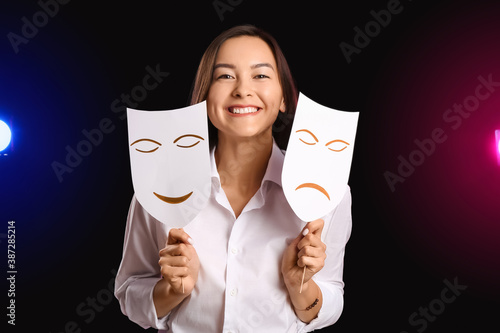 Fotografija Young talented actress with different masks on dark background