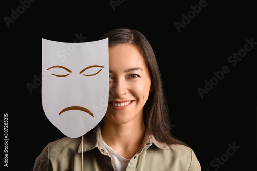 Fotografie Happy actress with sad mask on dark background