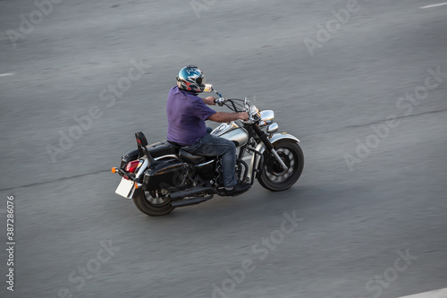 Motorcycle Rider in a Helmet Moves on a Motorcycle along the road.
