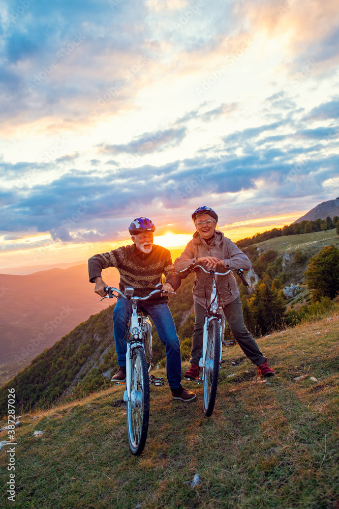 Active Senior Couple Riding Bikes In Park Active Senior Couple Riding Bikes In Park