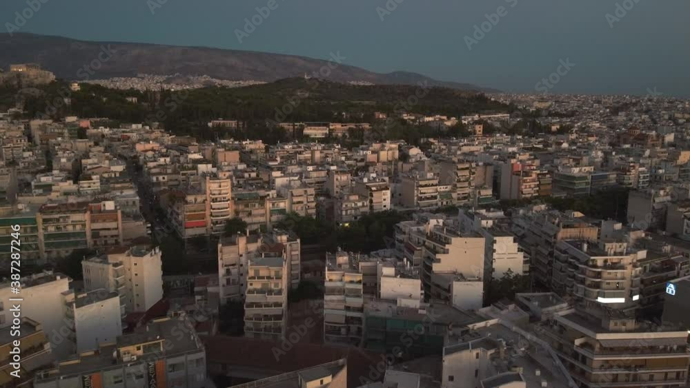 Aerial birds eye shot of lighting downtown of Athens during sunset with mountains in background.