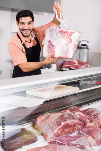 Active butcher is demonstraiting meat to clients indoors