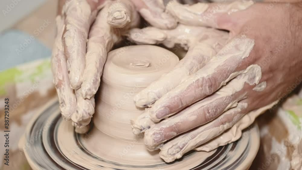 Couple working on pottery wheel. Top view of woman and man hands making ceramic pot or sculpting clay Couple working on pottery wheel. Top view of woman and man hands making ceramic pot or sculpting clay
