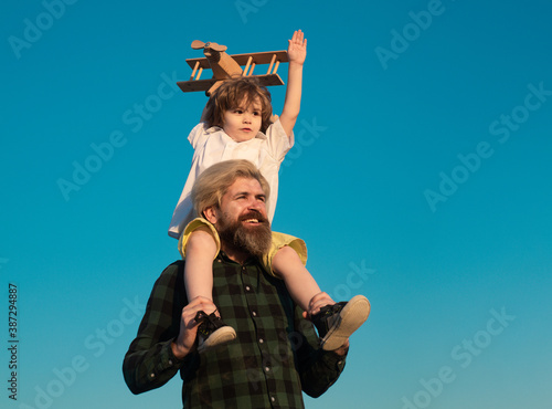 Father and son together. Sweet childhood. Boy child is sitting on daddy shoulder piggyback while the flight.