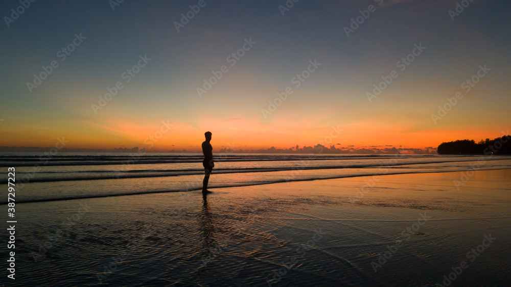 young man standing on the beach with a beautiful sunset young man standing on the beach with a beautiful sunset