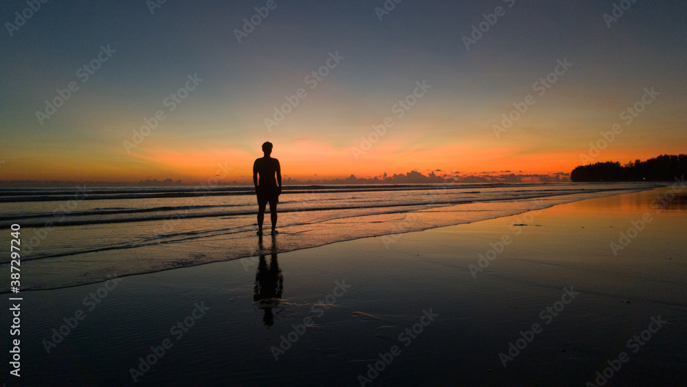 young man standing on the beach at beautiful sunset