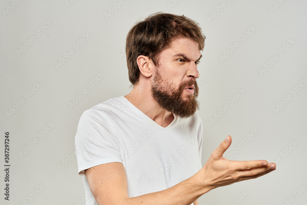 bearded man gesturing with his hands in a white t-shirt aggression light background bearded man gesturing with his hands in a white t-shirt aggression light background