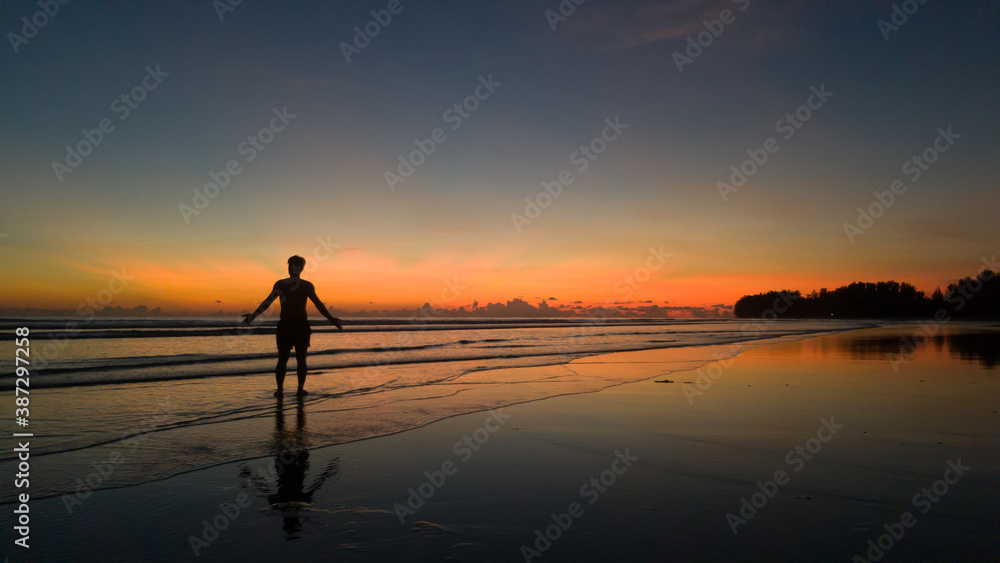 young man standing on the beach at beautiful sunset