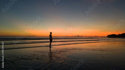 young man standing on the beach with a beautiful sunset