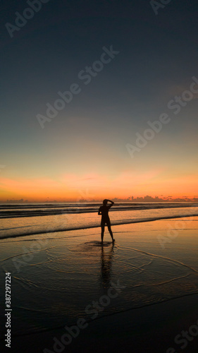 young woman standing on the beach with a beautiful sunset