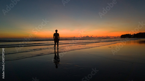 young man standing on the beach at beautiful sunset