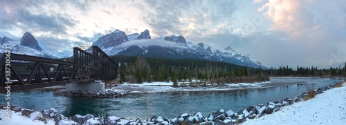Bow River and Engine Bridge Panoramic Landscape with Rugged Mountain Peaks of Rundle Range above City of Canmore on a cold October Day in Canadian Rocky Mountains