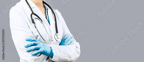 Female Doctor with crossed hands over grey background. Impersonal no face. Medical banner. Copy space. Book appointment or checkup time reminder. Doctors advice
