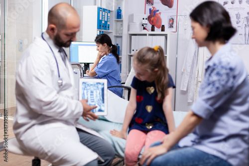 Doctor holding tablet with radiography during medical examination of child consultation. Healthcare physician specialist in medicine providing health care services treatment examination.