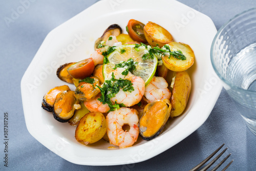 Delicious stewed slices of potato with seafood - shrimps and mussels