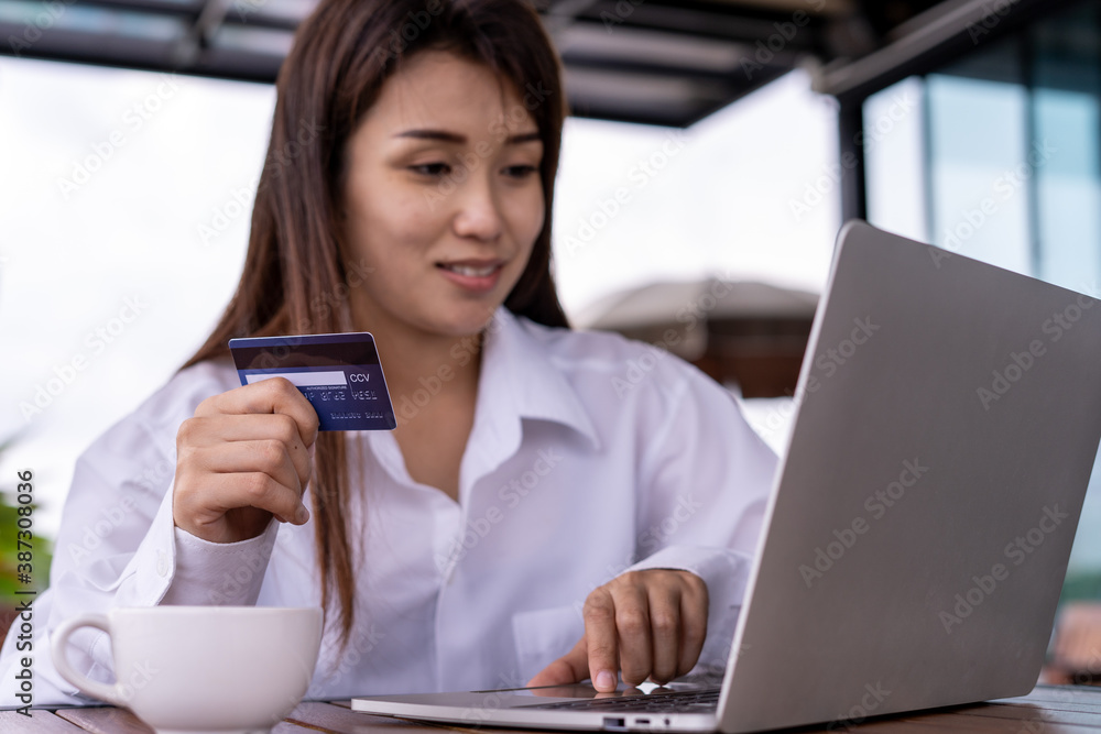 Asian women are paying online with a promo code from shopping discount card. Online shopping , payment concept Asian women are paying online with a promo code from shopping discount card. Online shopping , payment concept