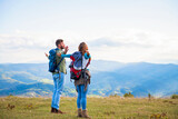 Happy travelers couple conquered top of mountain, raises hands up