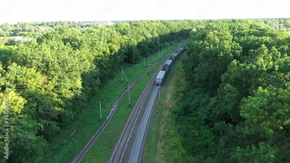 Following a train, tracking on a carriage - a train with carriages travels on railroad tracks among the green trees on a long turn. Following a train, tracking on a carriage - a train with carriages travels on railroad tracks among the green trees on a long turn.