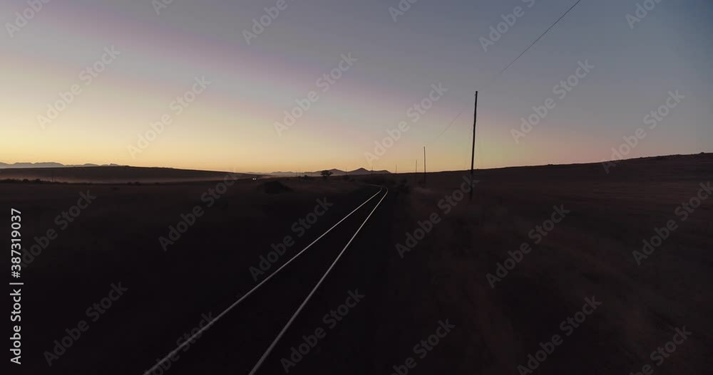 4K Drone shot tracking down shiny train lines before sunrise and passing by and under phone lines at the end of shot 4K Drone shot tracking down shiny train lines before sunrise and passing by and under phone lines at the end of shot