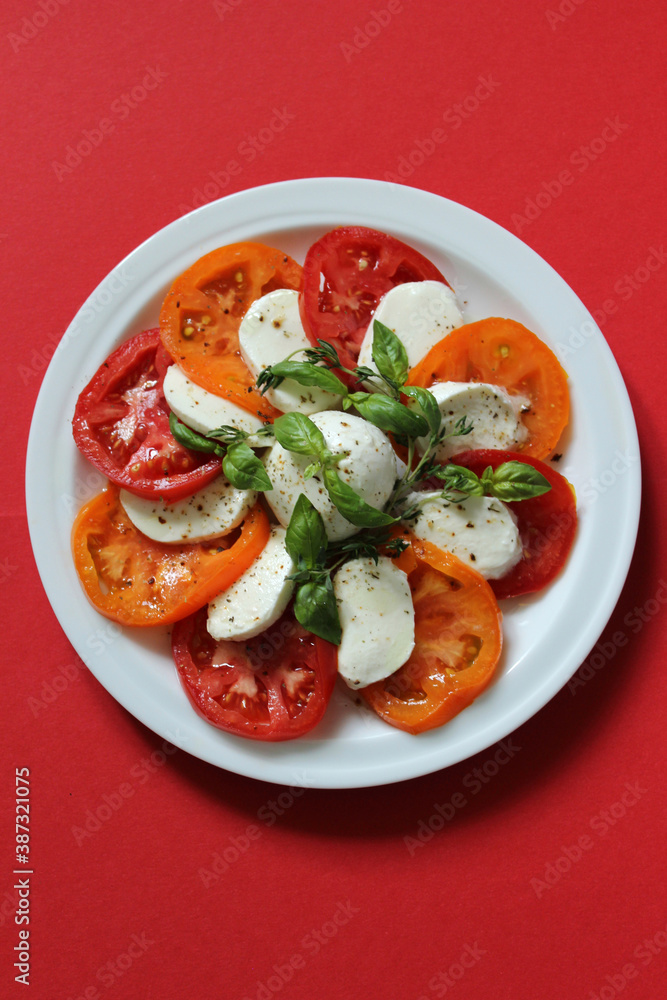 Vegetable salad with tomatoes and cheese on a red background Vegetable salad with tomatoes and cheese on a red background