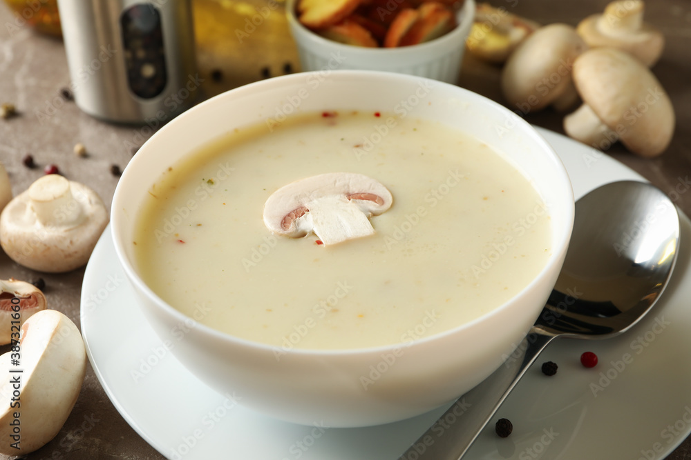 Concept of tasty lunch with bowl of mushroom soup on gray background Concept of tasty lunch with bowl of mushroom soup on gray background