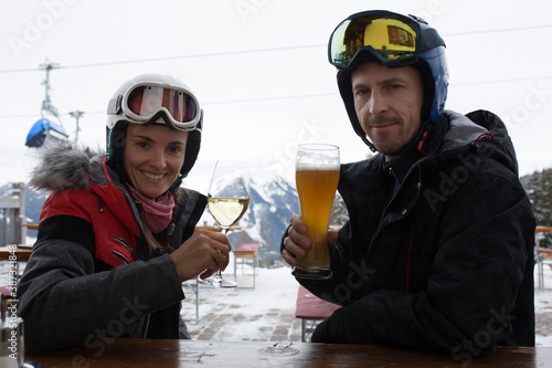 Woman and man, husband and wife, drinking beer and wine in a restaurant on a ski slope during ski break in the afternoon