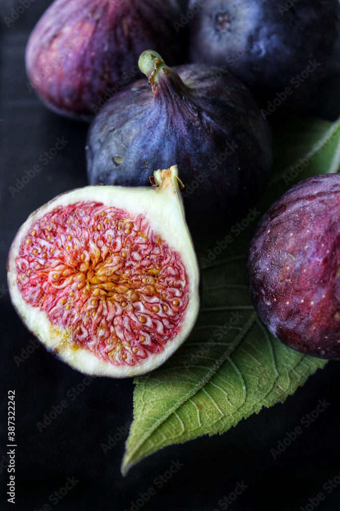 A slice of ripe figs with a green leaf on a dark background close-up A slice of ripe figs with a green leaf on a dark background close-up