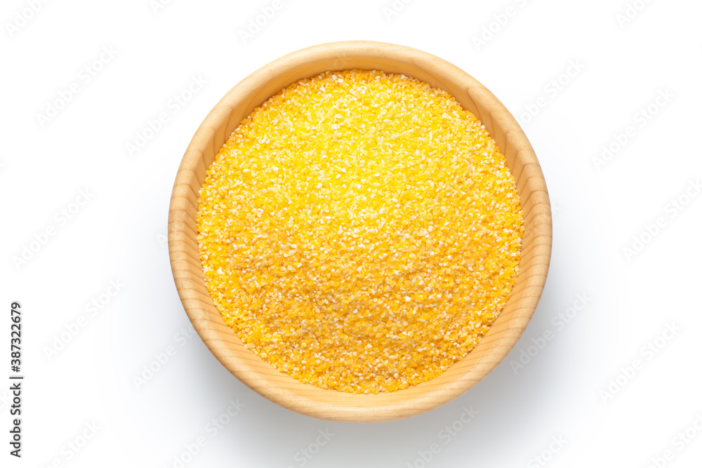 Corn grits in a wooden bowl isolated on white background. Top view.
