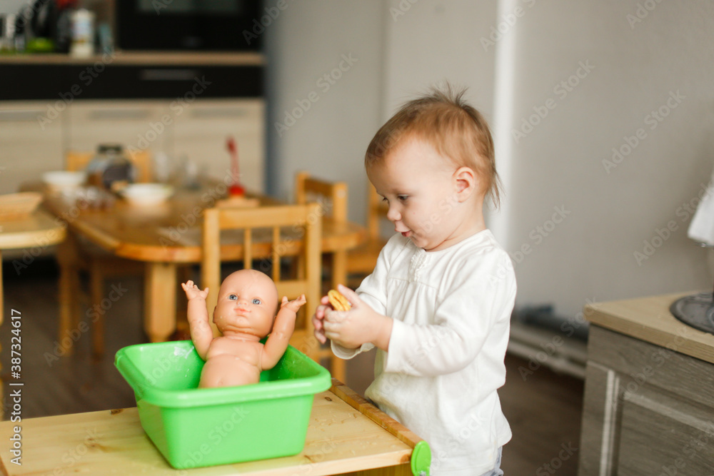 Toddler toddler bathes a toddler doll in a basin of water and a sponge, montessori and earlier child development Toddler toddler bathes a toddler doll in a basin of water and a sponge, montessori and earlier child development