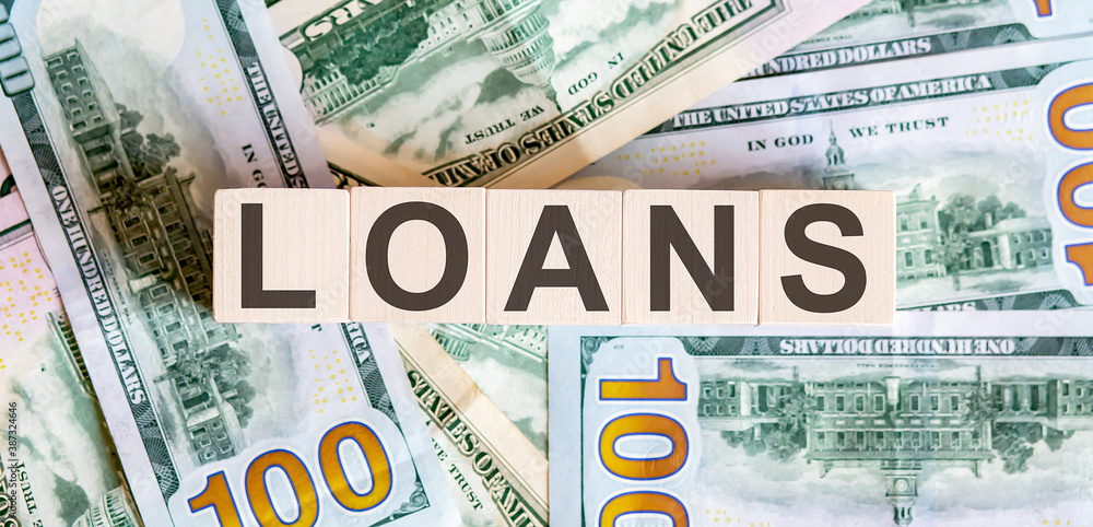 Concept words LOANS on wooden blocks on a beautiful background from dollar bills. Concept words LOANS on wooden blocks on a beautiful background from dollar bills.