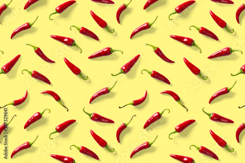 Creative background made of red chili or chilli on yellow backdrop. Minimal food backgroud. Red hot chilli peppers background.