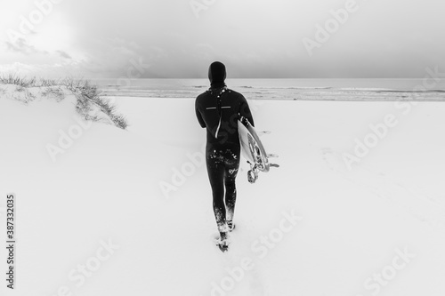 Obraz na plátně Surfer in wetsuit with surfboard running to ocean