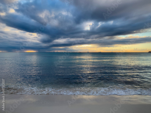 Breathtaking sunrise over Caribbean sea  with blue low clouds  first rays of the sun  and calm sea surface view from the beach