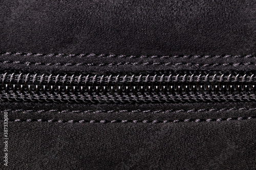 Zip fastener background texture. A high-resolution closeup of a detail from a closed plastic zip fastening on black suede shoe. Macro photo.
