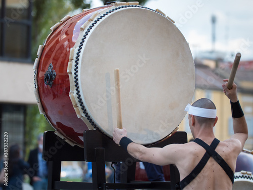 Man with Headband Playing Vertical Drum of Japanese Musical Tradition during a Public Outdoor Event