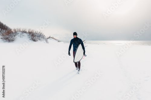 Snowy winter and surfer with surfboard. Winter and surfer in wetsuit. © artifirsov