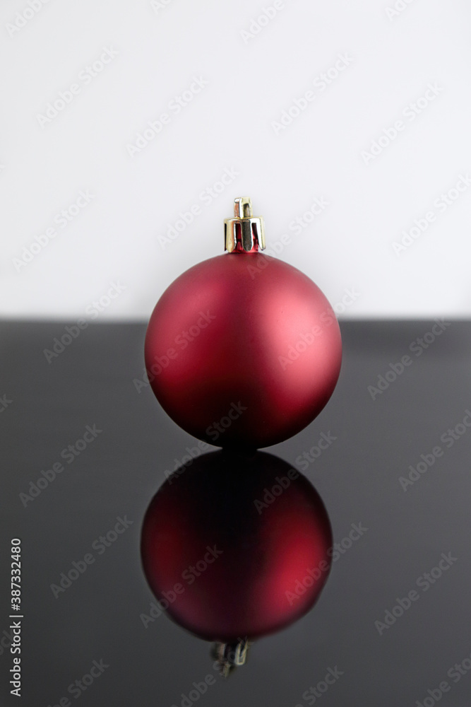 Red christmas ball reflected on a black table and white background. Copy space. Red christmas ball reflected on a black table and white background. Copy space.