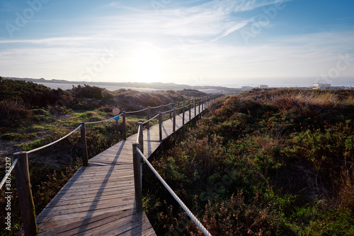 Wooden pedestrian walkway through Sintra-Cascais natural park. Wild sandy landscape  with part of Cresmina Dunes. Beautiful scenery in Portugal.