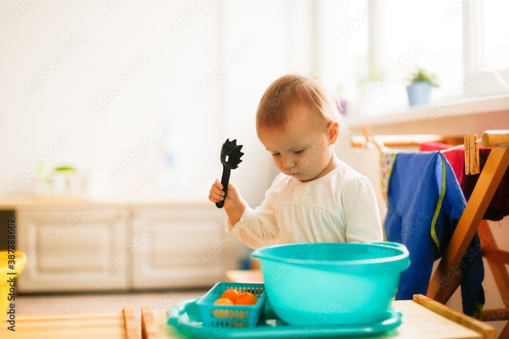 Toddler child plays with water in a basin, developing sensory activities with water and objects, montessori and earlier child development, toddler independence Toddler child plays with water in a basin, developing sensory activities with water and objects, montessori and earlier child development, toddler independence
