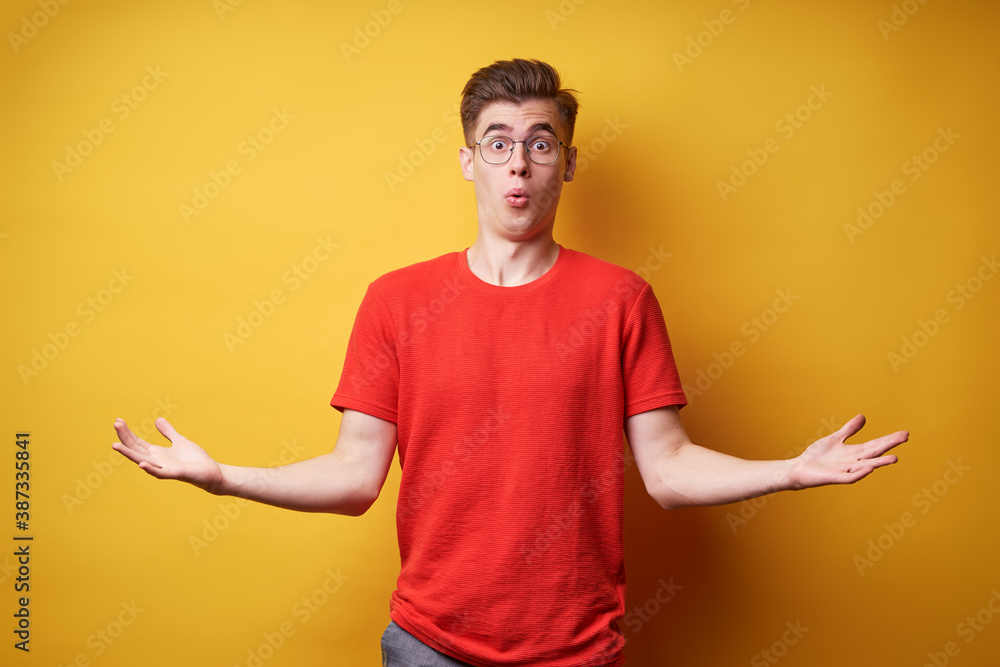 Don't know! Confused young man against yellow background.