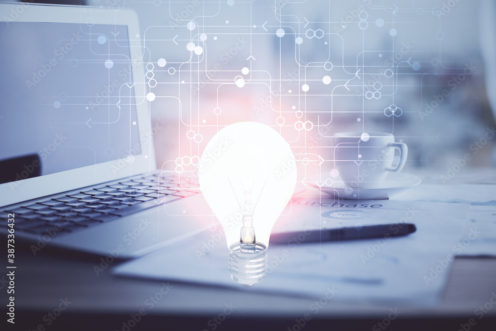 Computer on desktop in office with bulb icon hologram. Double exposure. Concept of idea. Computer on desktop in office with bulb icon hologram. Double exposure. Concept of idea.