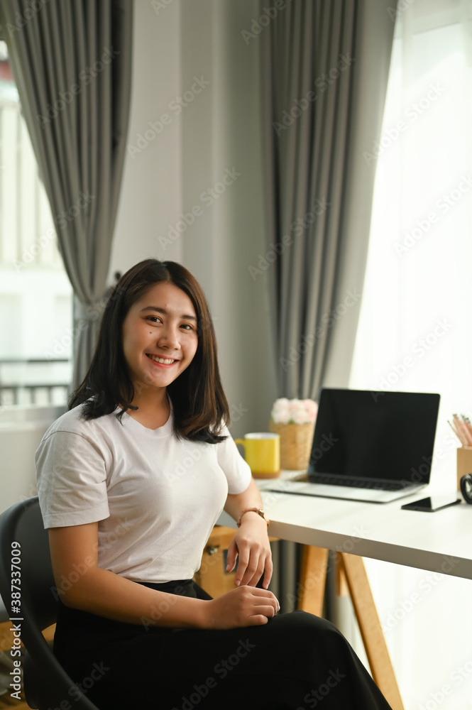 Portrait of female smile and looking into camera while sitting in home office. Portrait of female smile and looking into camera while sitting in home office.