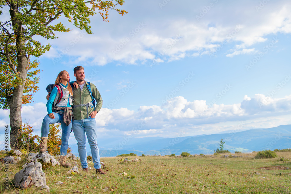 Happy couple hiking and enjoying a valley view Happy couple hiking and enjoying a valley view